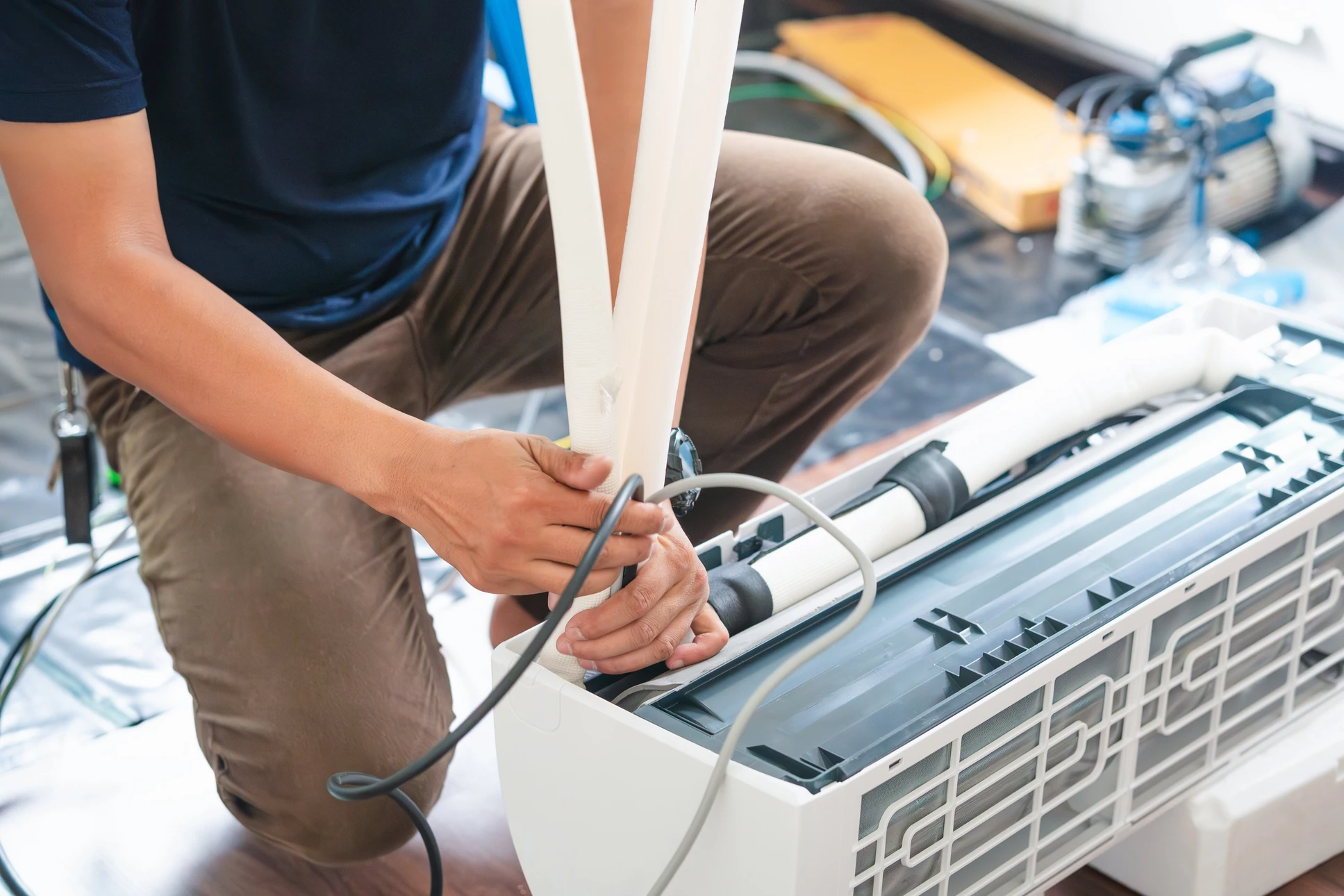 Technicien en salopette bleue effectuant la maintenance d'un radiateur à ailettes dans un intérieur résidentiel moderne