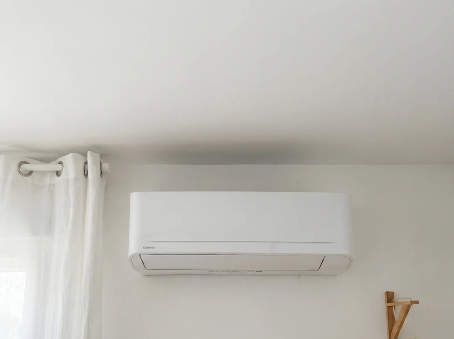 Intérieur d'une chambre aux murs blancs avec climatiseur mural split system de marque Toshiba monté en hauteur