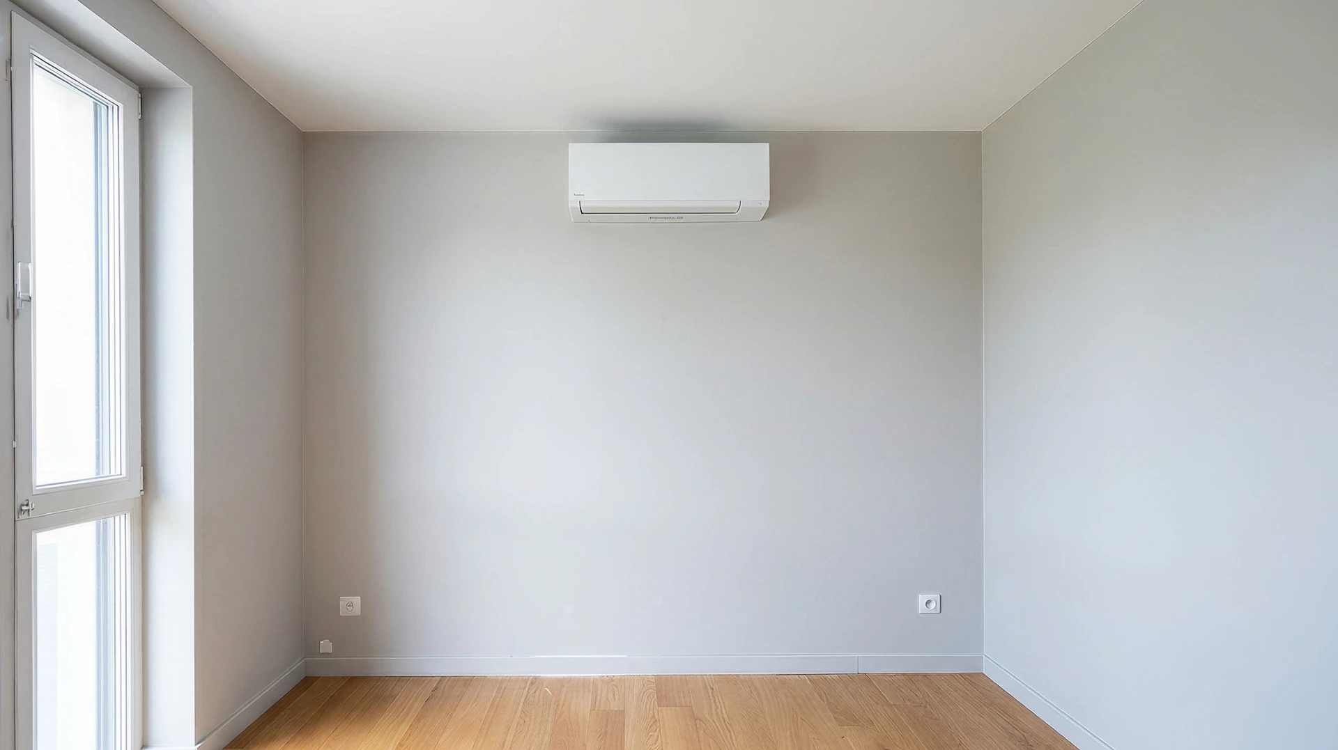 Technicien en climatisation travaillant en extérieur, agenouillé près d'une unité de climatisation