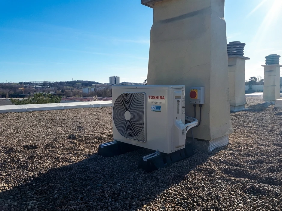 Intérieur d'une pièce aux murs beige clair, avec une unité intérieure de climatiseur mural split-system blanc installée en hauteur, près du plafond blanc